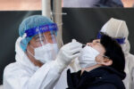 A healthcare worker collects a swab sample from a man to test for the coronavirus disease (COVID-19), at a temporary testing site set up at a railway station, in Seoul, South Korea, February 10, 2022.  REUTERS/ Heo Ran